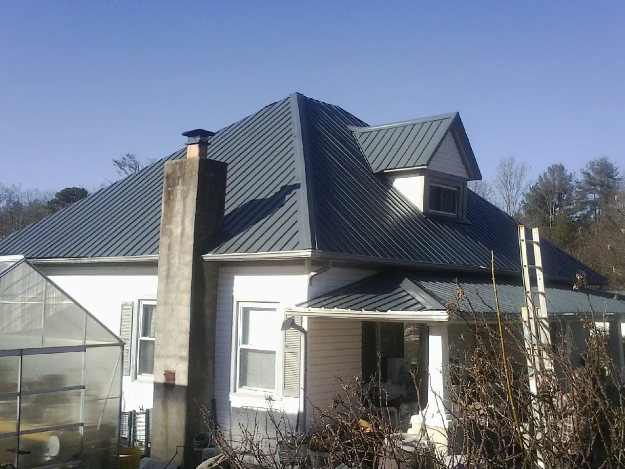 Dark blue standing seam metal roof on a white farmhouse with dormer — Slate & Tile Roof Repair by Roofing Brothers in Knightsen
