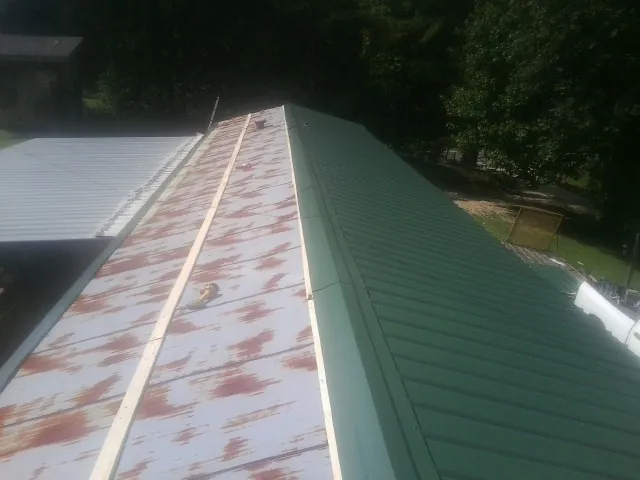 Old rusted panels beside newly installed green metal roofing — Wind Damage Roof Repair by Roofing Brothers in Knightsen