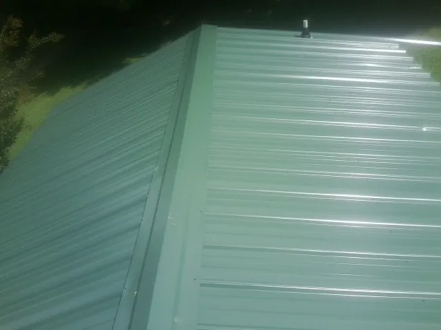 New green metal panels meeting at the ridge of a roof — Flat Roof Repair work by our crew in Knightsen