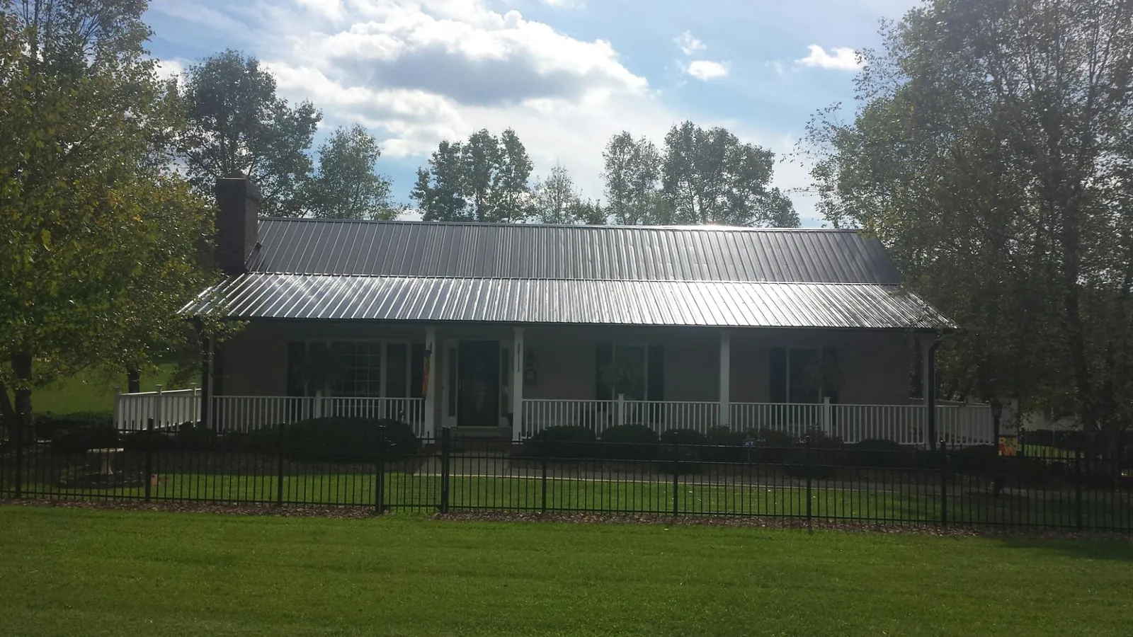 Gray metal roof on a brick ranch with a full width front porch — Gutter Guard Installation work by our crew in Knightsen