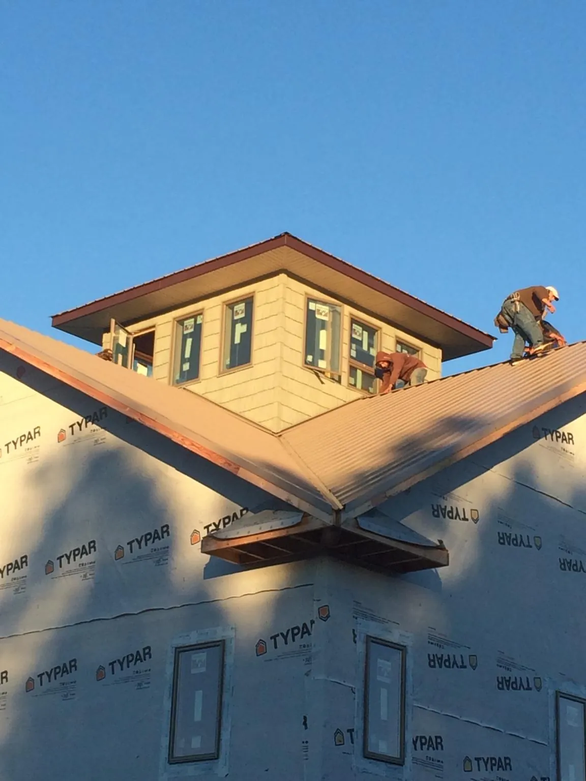 Roofers working around a rooftop cupola on a new metal roof at sunset — Roof Waterproofing in Knightsen by Roofing Brothers